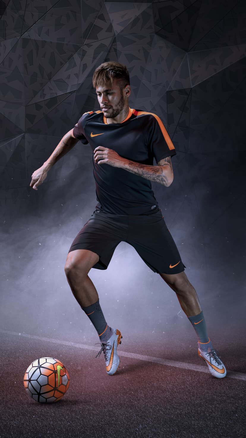 Neymar Jr. in Nike athletic wear poses near a soccer ball against a dark geometric textured background.
