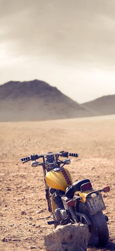 Yellow Motorcycle in Desert Landscape with Mountains