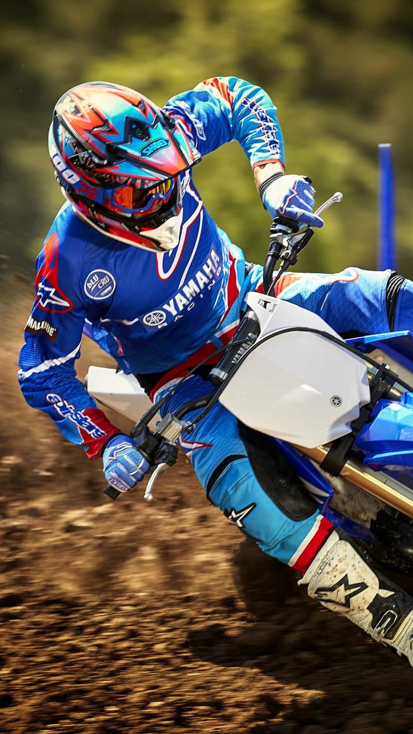 Motocross rider in blue and red gear leans a dirt bike into a dusty track turn during an intense off-road race.
