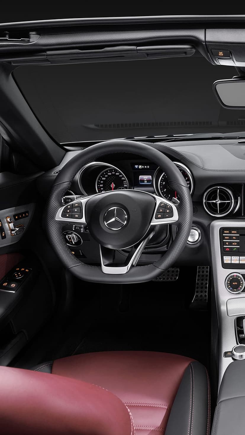 Mercedes SLK interior featuring red leather seats, a multi-function steering wheel, and silver air vents.