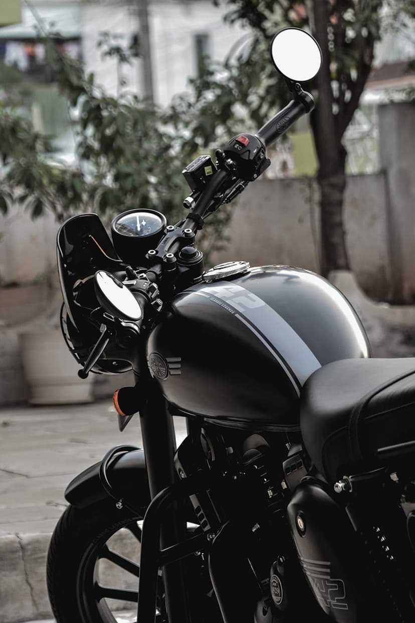 Black Jawa motorcycle with a grey stripe on the tank, chrome mirrors, and a round headlight against a blurred background.