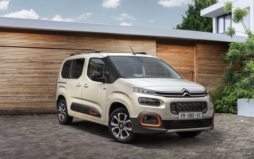 Beige Citroën Berlingo XTR van with orange accents on a stone driveway in front of a modern wooden building.