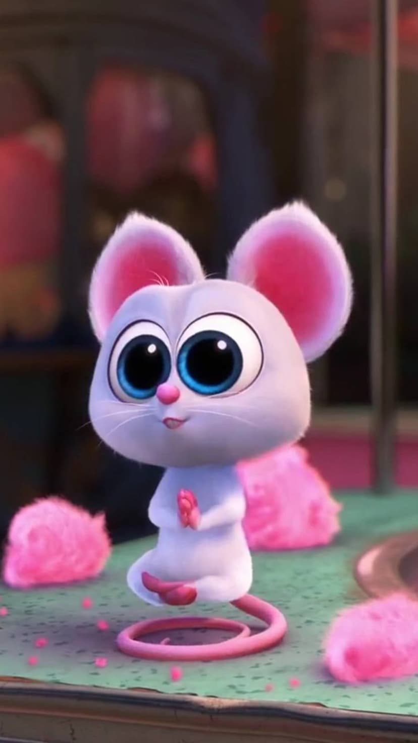 Mouse with large blue eyes and pink ears sits with paws together surrounded by soft pink petals and fluffy decor.