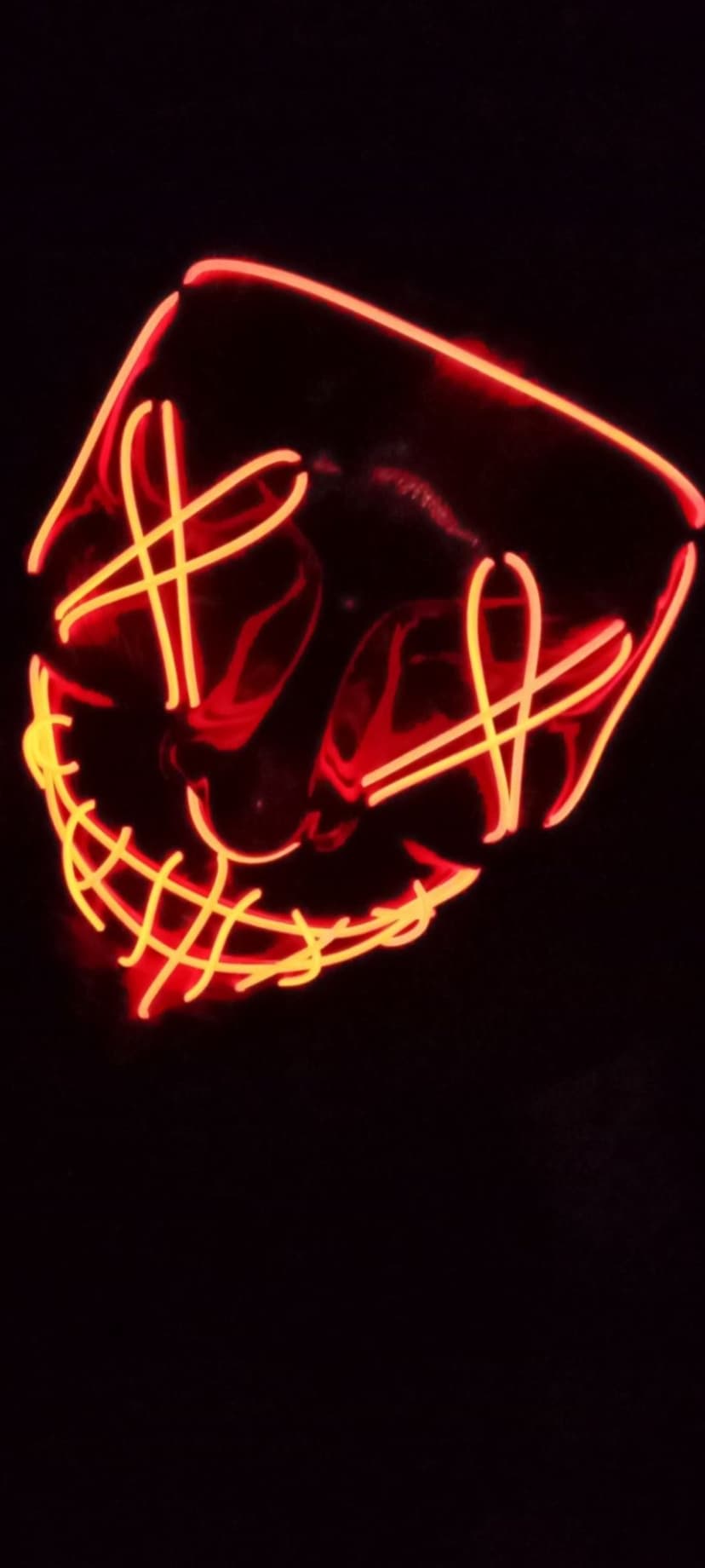 Purge mask featuring glowing red and yellow neon wire stitches over the mouth and eyes against a black background.