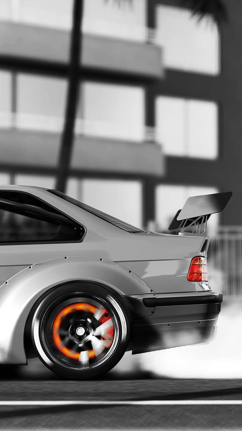 Silver BMW M3 E36 drift car with a widebody kit, large rear spoiler, and a glowing red brake rotor in the city.