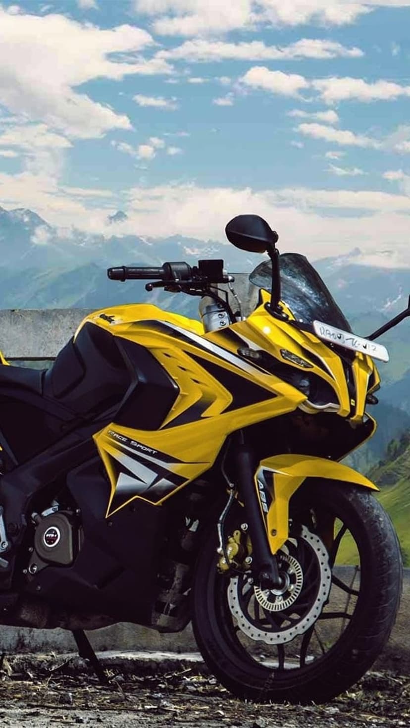 Yellow sport motorcycle parked on a winding asphalt mountain road beneath a vast, cloudy sky during daytime.