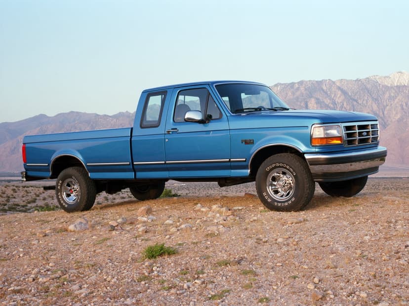 Blue Ford F-150 SuperCab parked on rocky desert ground with towering mountains and a clear sky in the background.