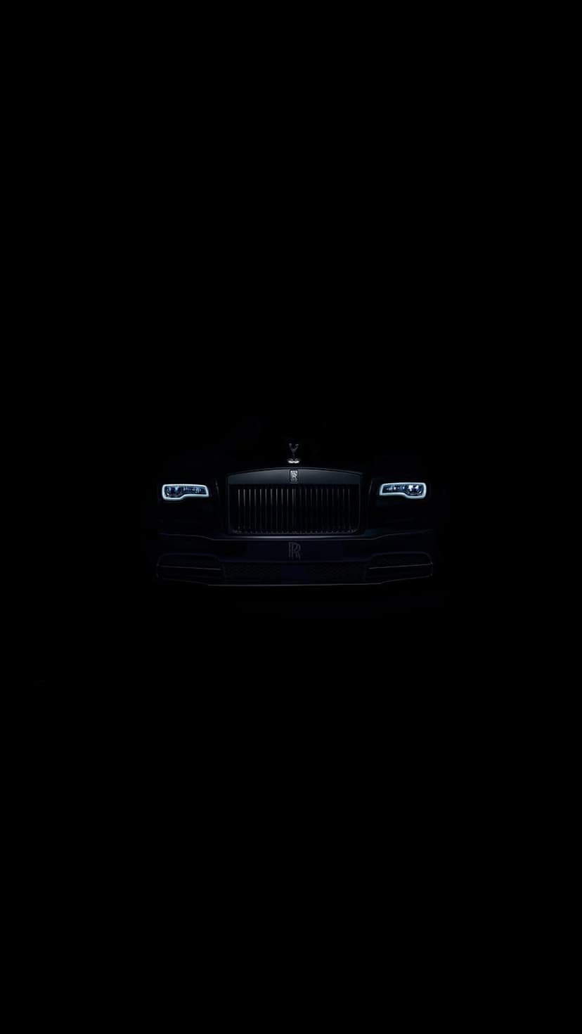 Rolls-Royce Wraith front grille and glowing LED headlights emerge from a dark, minimalist black background.