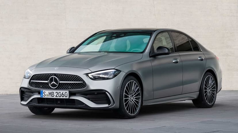 Silver Mercedes-Benz C-Class sedan parked against a neutral textured wall with soft studio lighting.