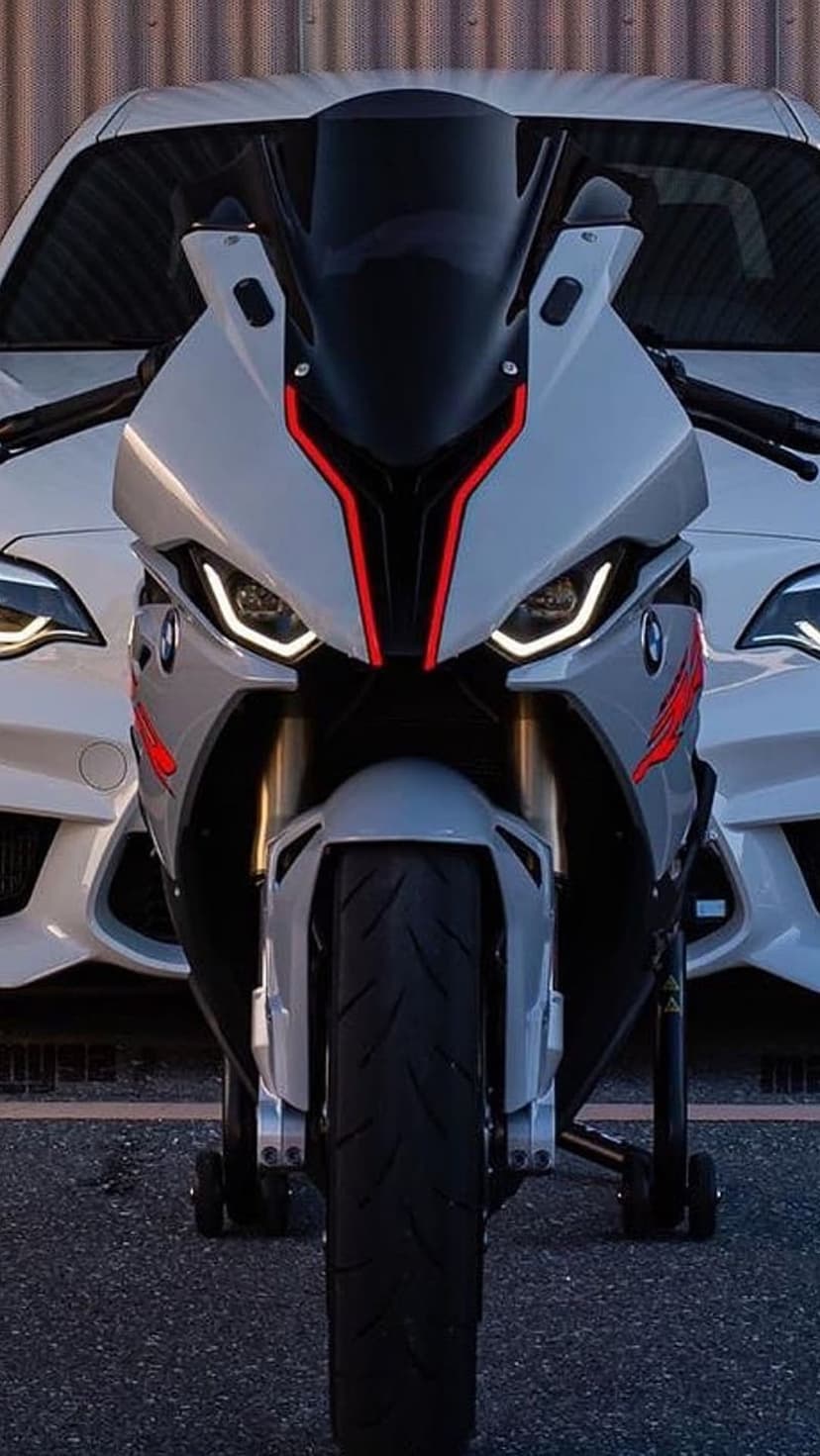 BMW S1000RR motorcycle with red accents and LED headlights parked in front of a white car in portrait view.