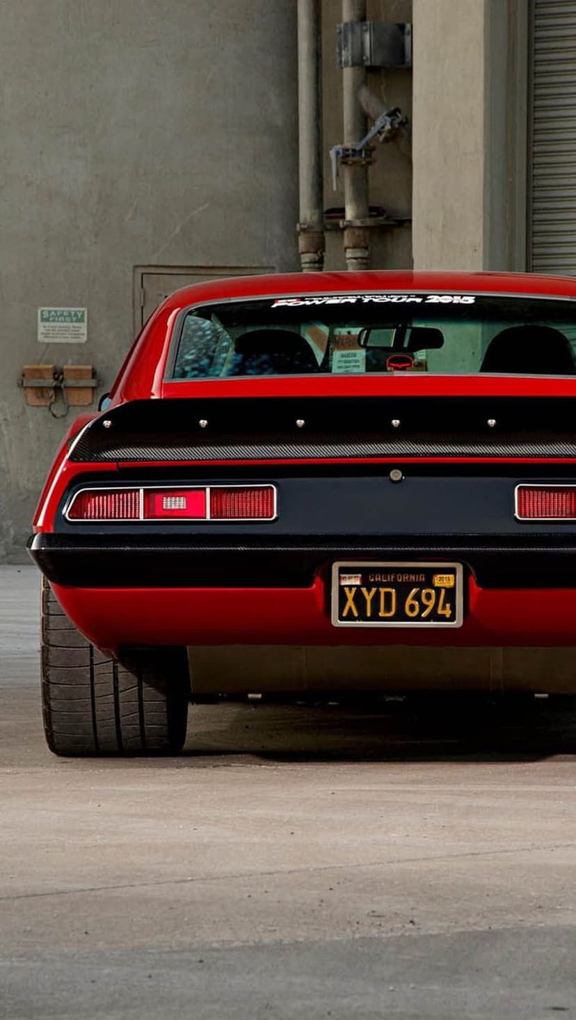Red classic muscle car rear view featuring a black carbon fiber spoiler and California license plate XYD 694.