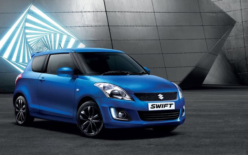 Blue Suzuki Swift hatchback with glowing headlights in a modern architectural garage with a spiraling light tunnel.