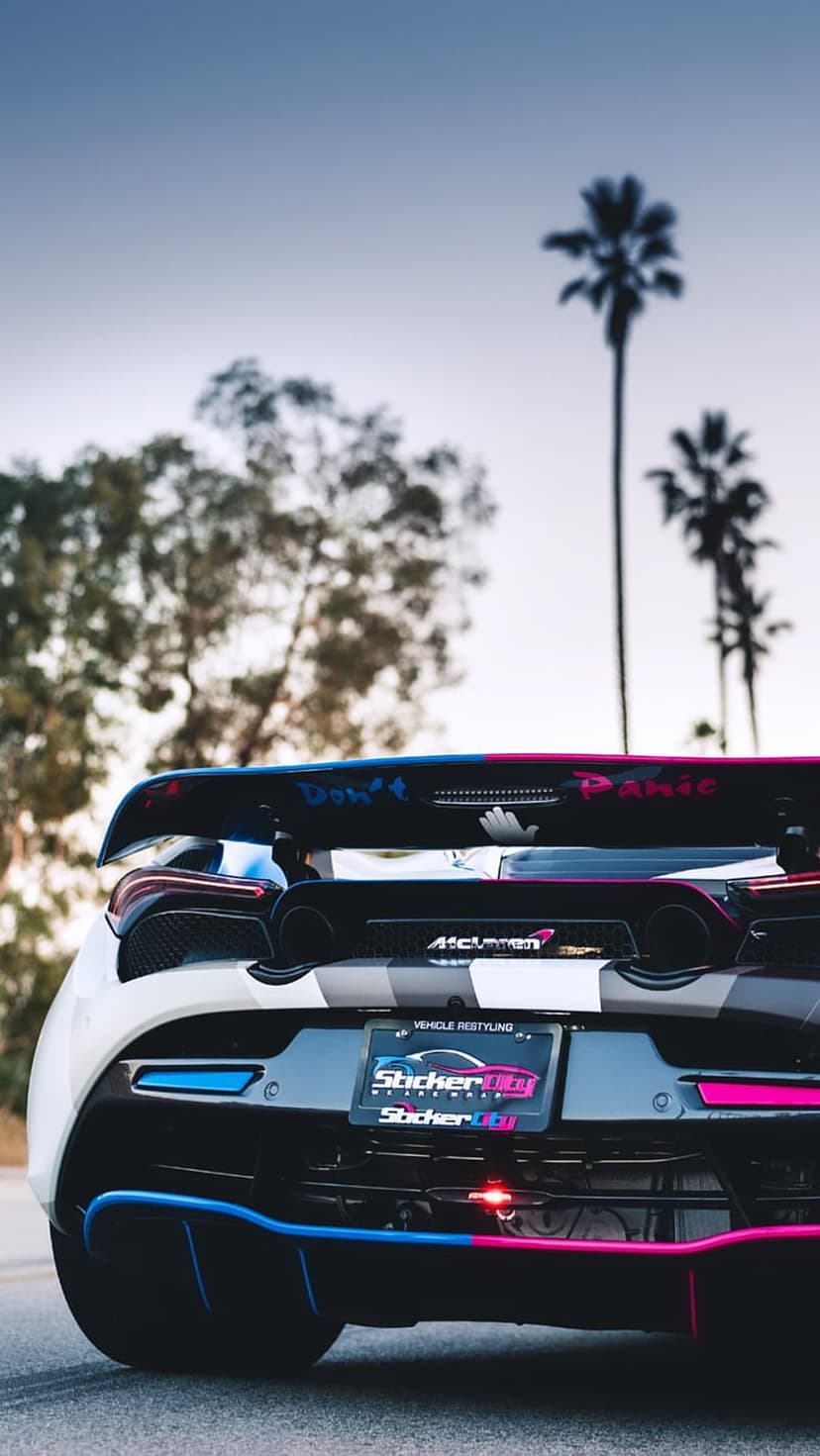 McLaren 720S rear view with pink and blue neon accents on a custom wrap against a tropical palm tree background.