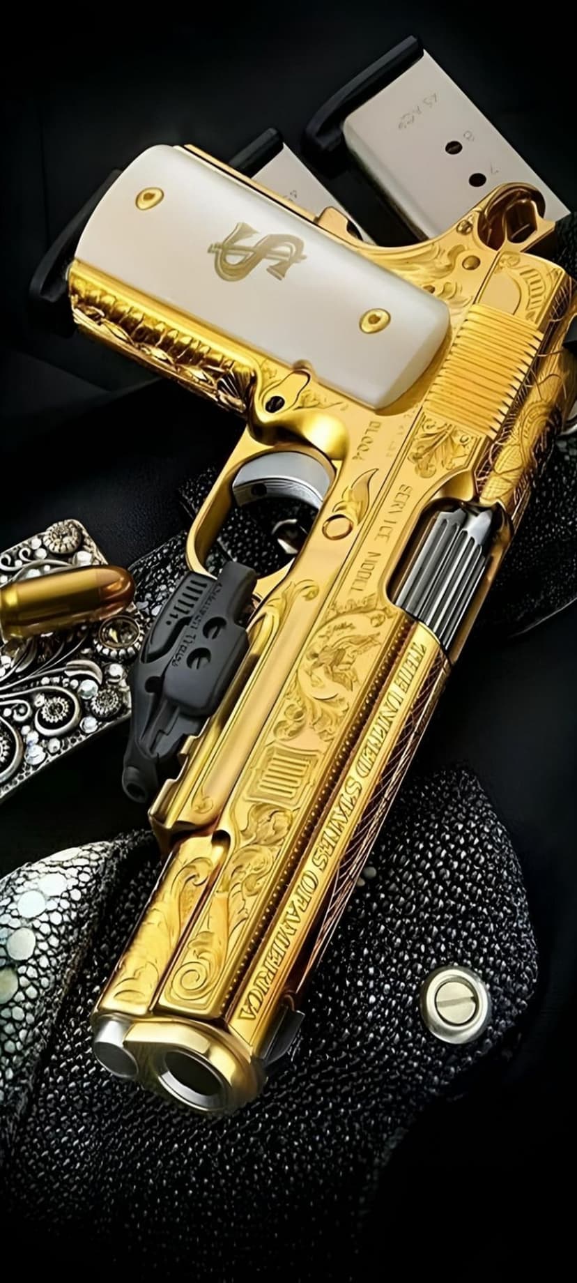 Gold-plated 1911 pistol with white dollar sign grips and scrollwork engraving on a textured black surface.