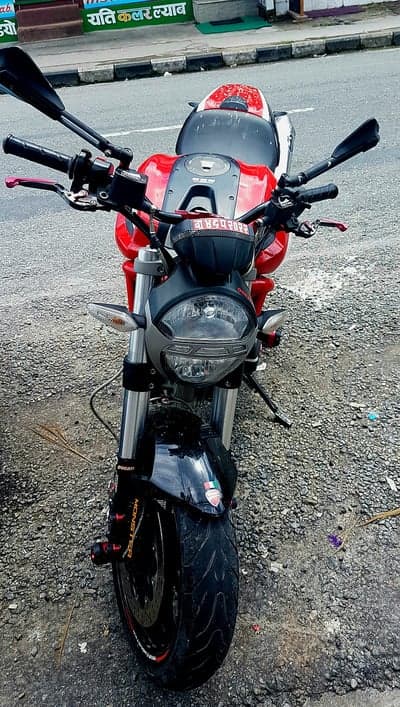 Red Ducati Monster Motorcycle parked on gravel road