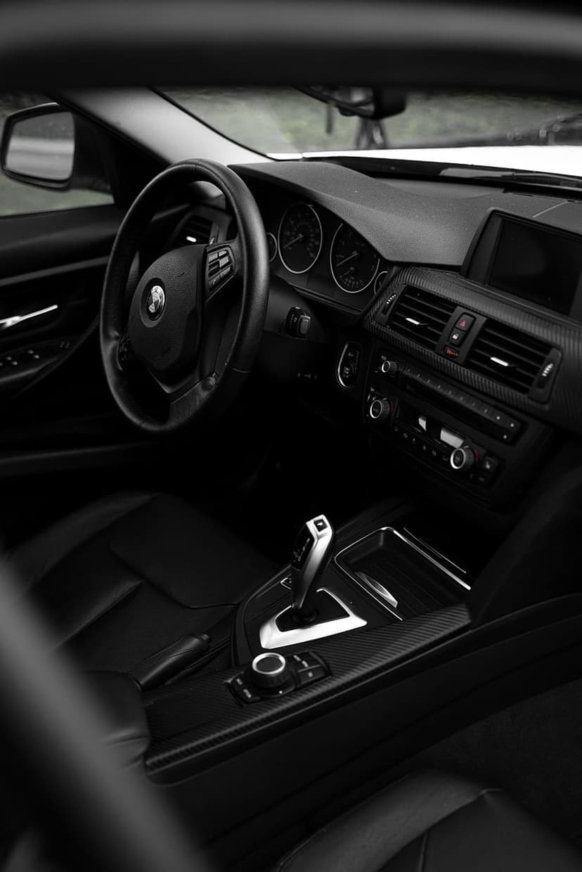 BMW M Sport steering wheel with blue and red stitching beside a digital dashboard and leather gear selector.