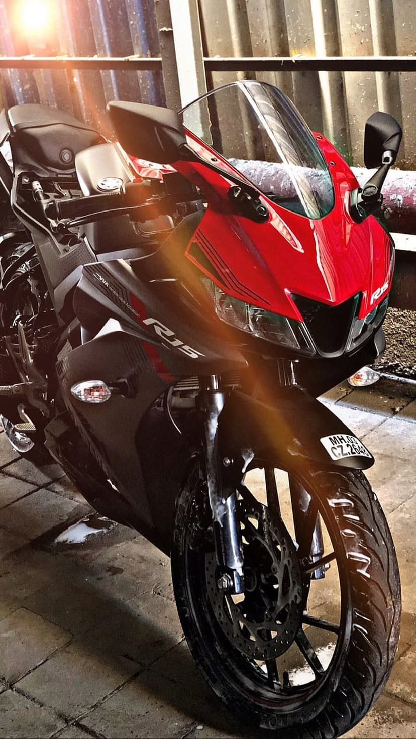 Yamaha R15 motorcycle featuring a red front fairing, black handlebars, and disc brakes on a tiled surface.