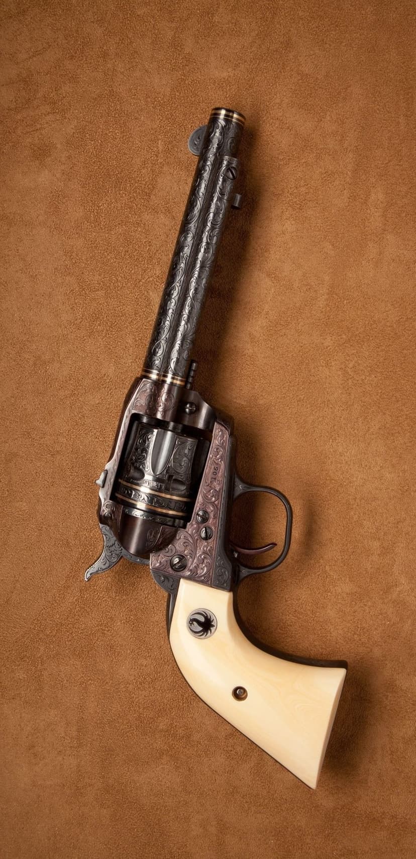 Engraved single-action revolver with ivory grips and a black spider emblem resting on textured brown suede.