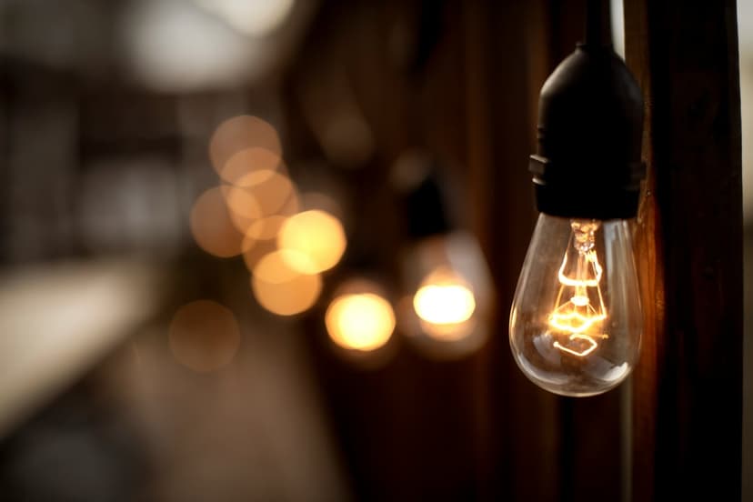 Vintage Edison bulb with glowing filaments and golden bokeh circles in a vertical mobile-friendly composition.