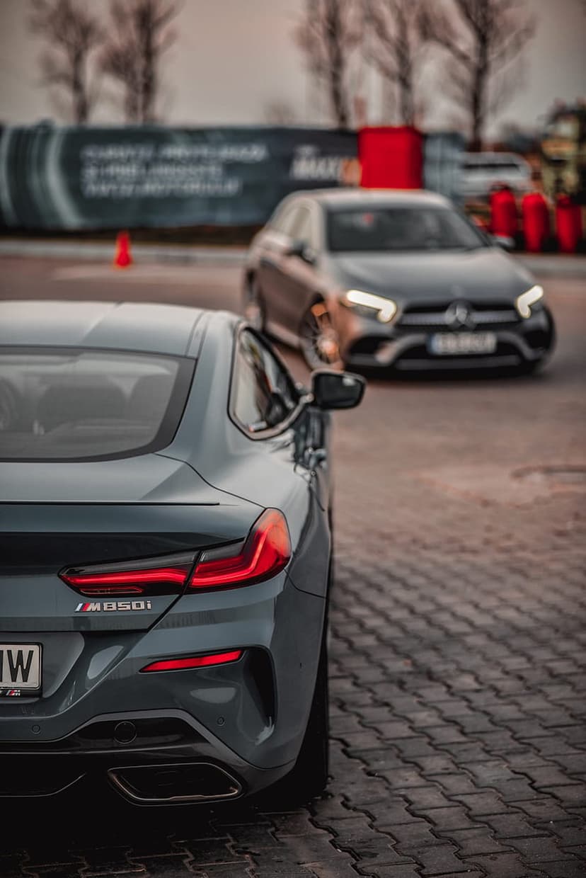 BMW M850i rear taillights and badging on an urban street with a blurred Mercedes-Benz in the background.
