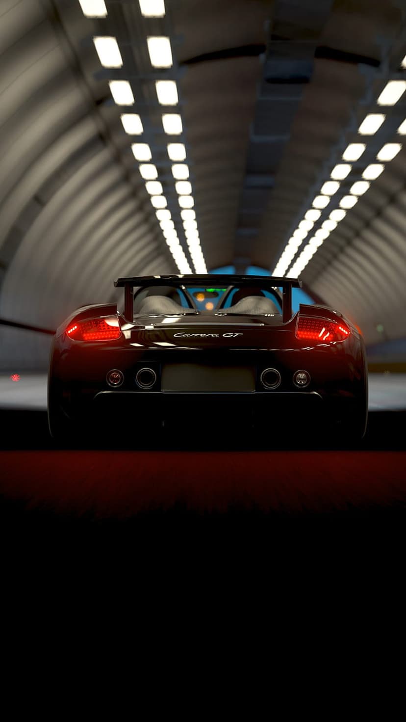 Red Porsche Carrera GT rear view speeding through a brightly lit tunnel with glowing taillights on wet pavement.