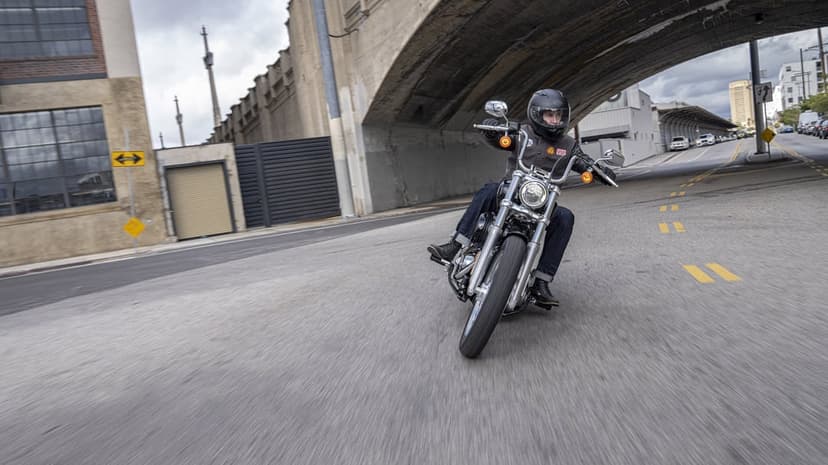 Black cruiser motorcycle being ridden under a concrete bridge with realistic motion blur on the asphalt road.