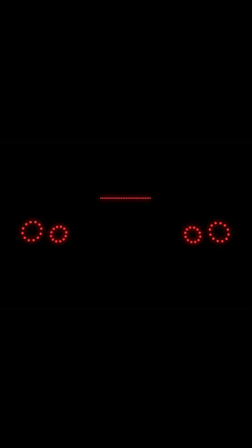 Red circular LED tail lights and a horizontal light bar glow against a stark black nocturnal background.