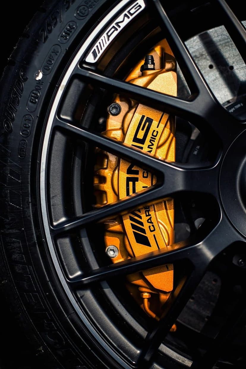 Gold AMG brake calipers and a carbon ceramic disc are visible through the spokes of a black sports car wheel.