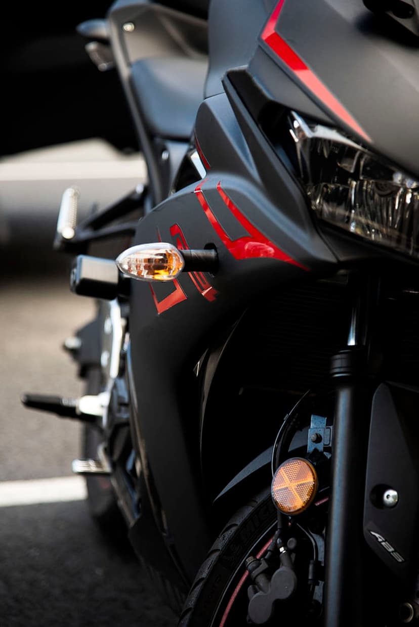 Black sportbike fairing with red flame graphics, a glowing orange turn signal, and a sharp headlight lens.