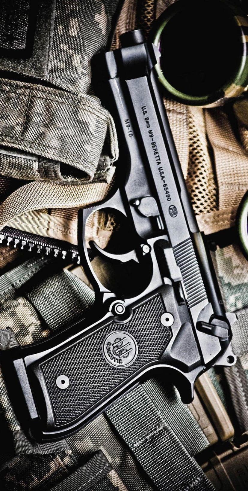 Beretta 92FS 9mm handgun resting on rugged green and brown tactical camouflage fabric with visible metal texture.