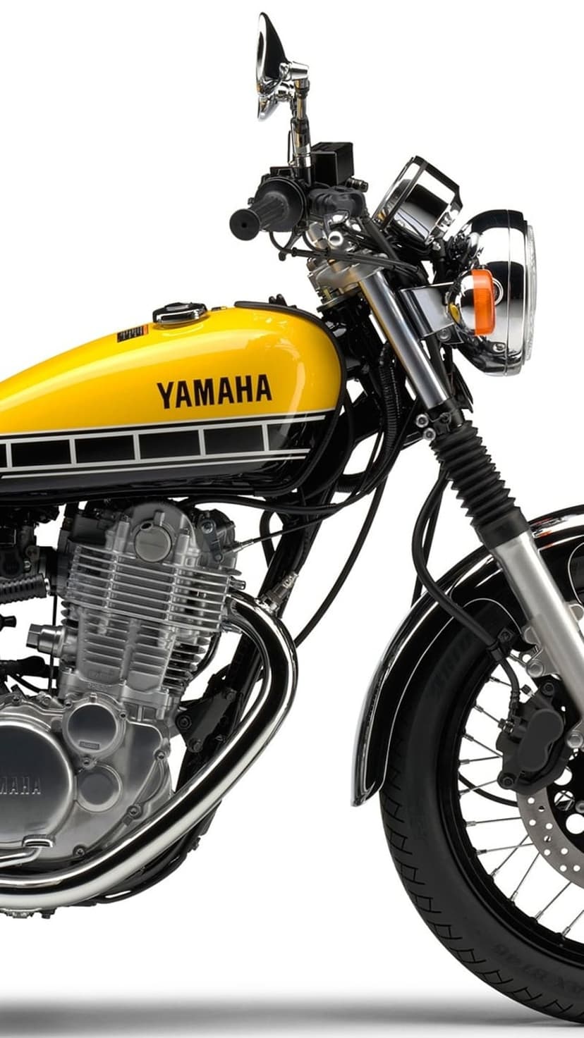 Yellow Yamaha fuel tank with black pinstripes above a silver engine and a chrome-spoked front wheel assembly.
