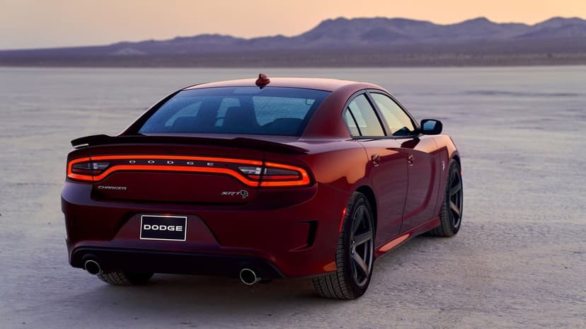 Maroon Dodge Charger SRT Hellcat with glowing tail lights on a salt flat desert landscape during sunset.