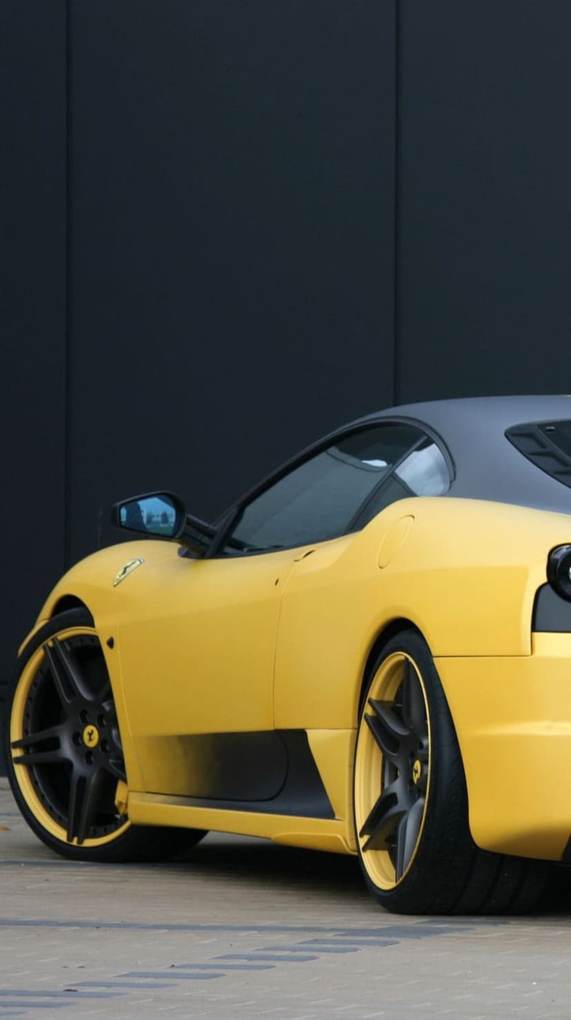 Ferrari 458 Italia in yellow with black multi-spoke wheels parked against a dark, minimalist matte background.