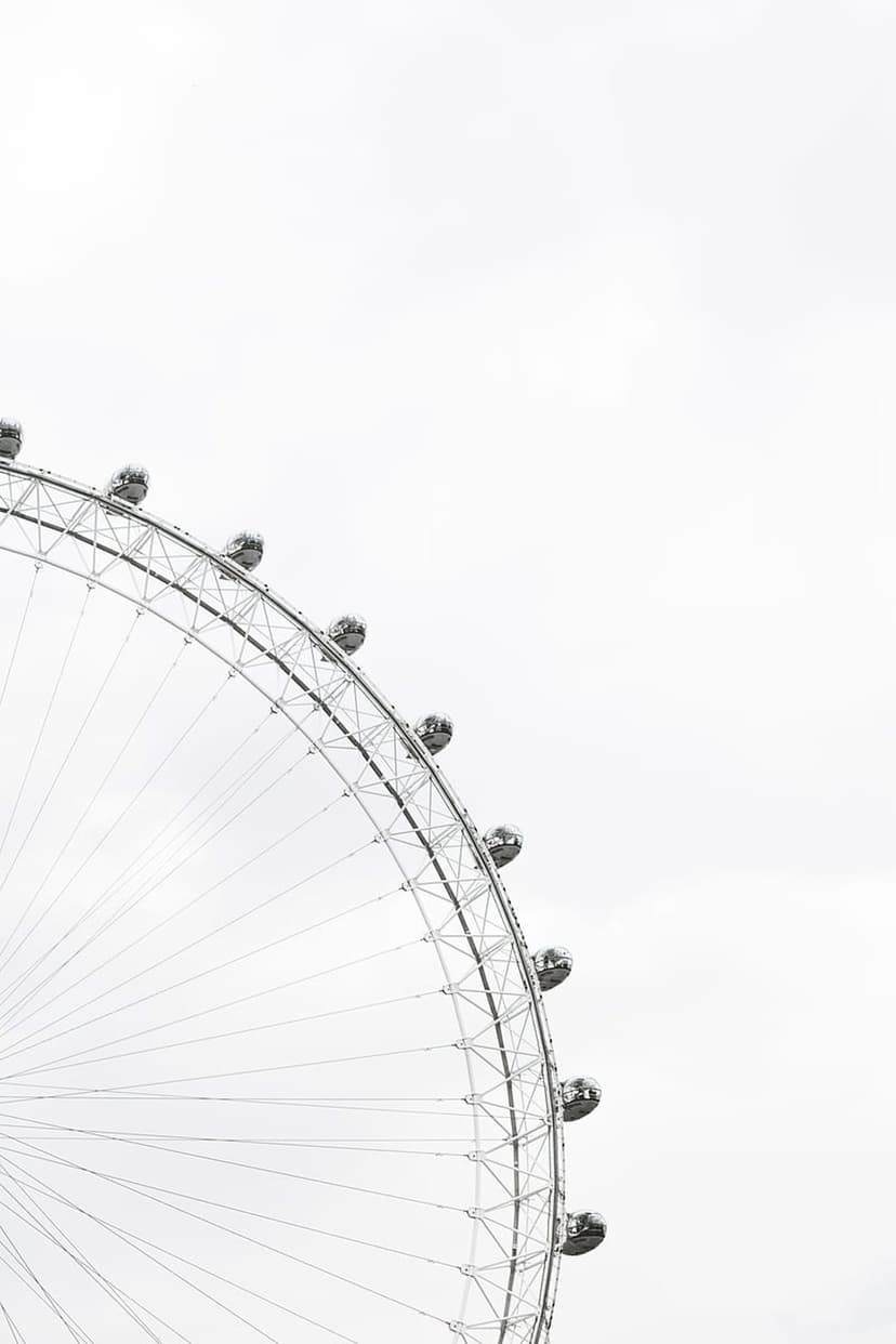 London Eye ferris wheel capsules and spokes against a bright white sky showcase intricate metal engineering.