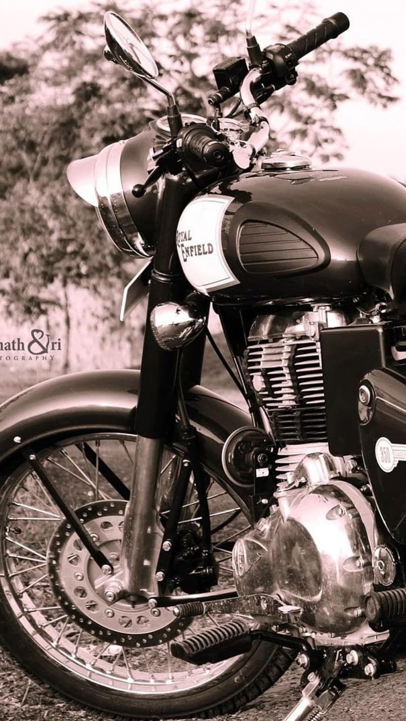 Royal Enfield Classic motorcycle front close-up showing chrome headlight and spokes in a sepia-toned portrait shot.
