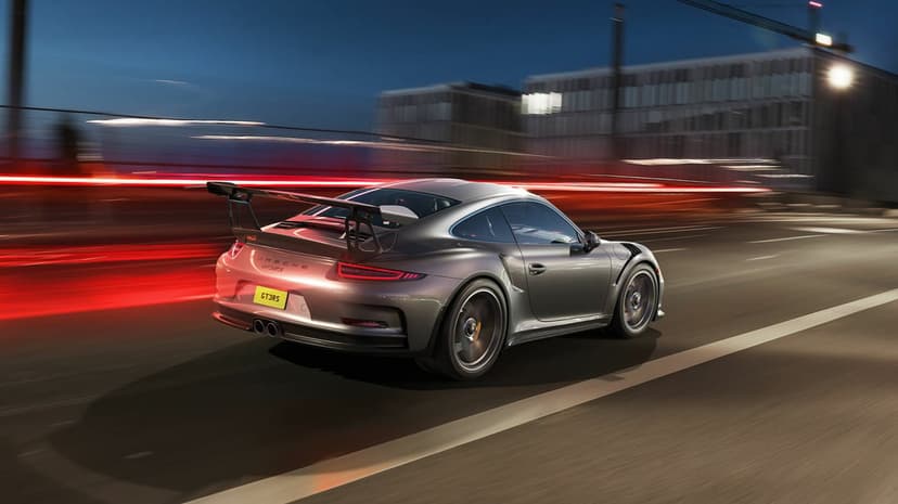 Silver Porsche 911 GT3 RS driving at night with motion blur, red light trails, and a city background.