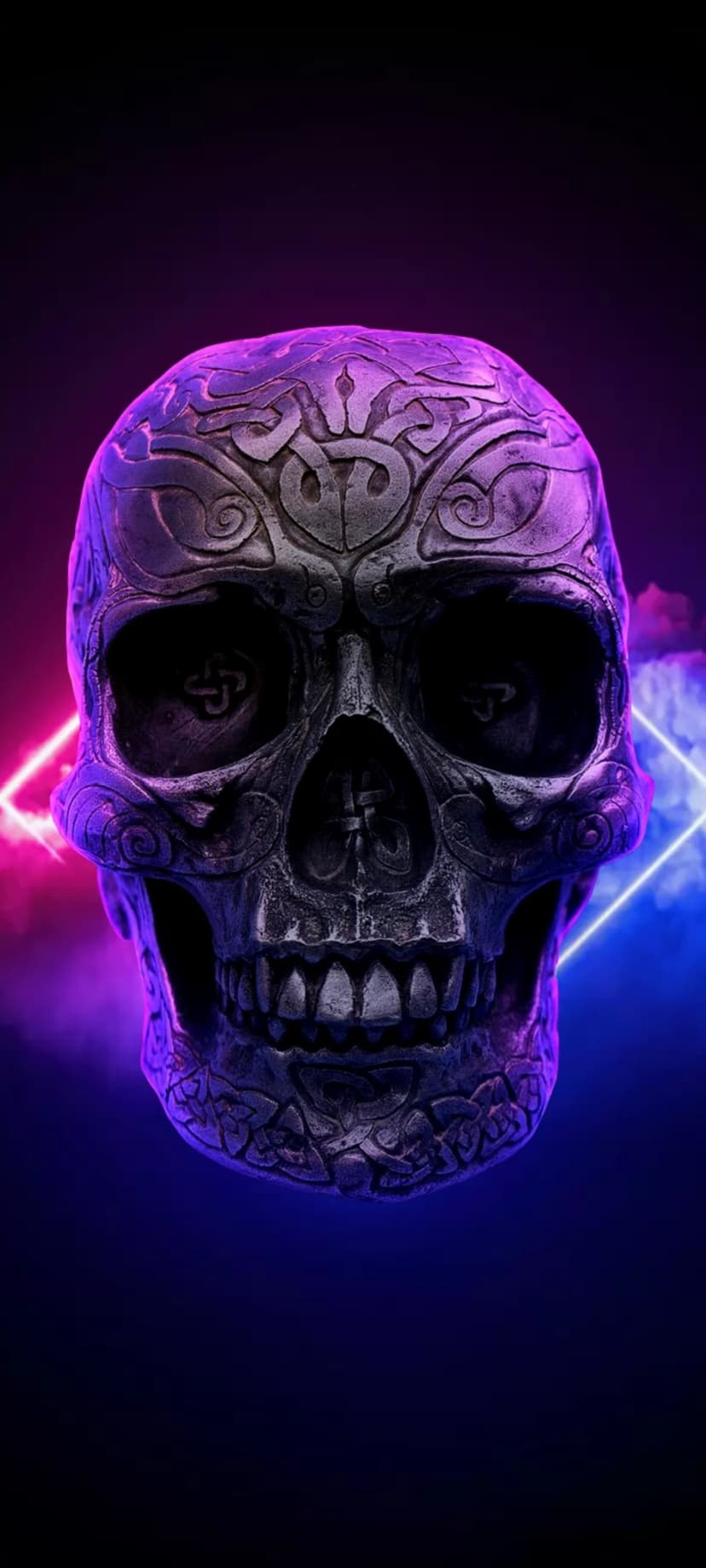 Carved gothic skull glows under pink and blue neon lights with wisps of colorful smoke in a dark setting.