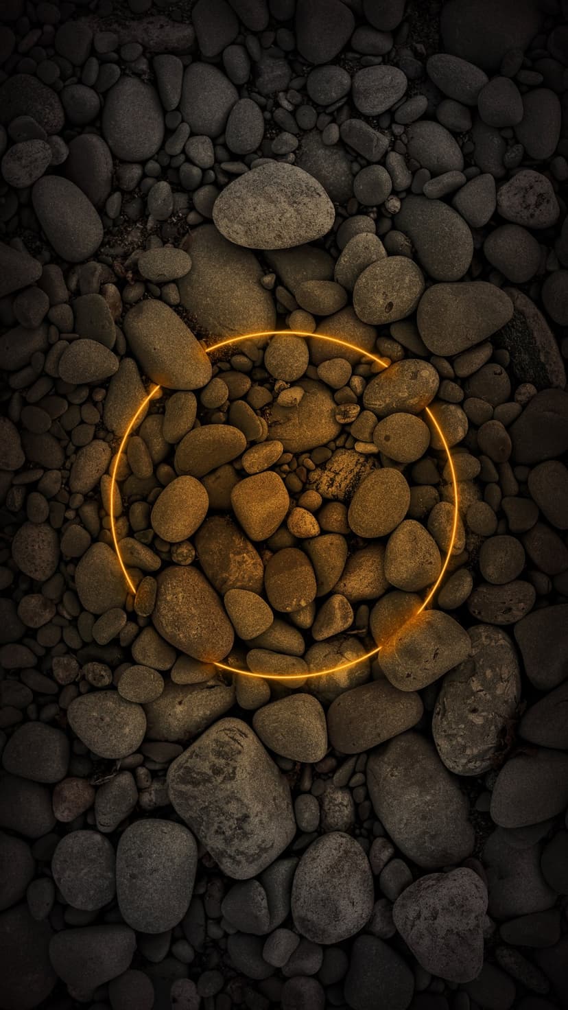 Glowing orange neon ring centered over a dense collection of smooth dark grey river pebbles in a top-down view.