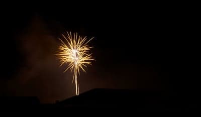 Golden Fireworks Explode Over Silhouetted Rooftops at Night
