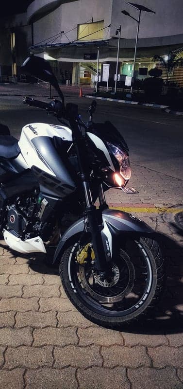 Nighttime Bajaj Pulsar NS200 motorcycle parked on patterned pavement