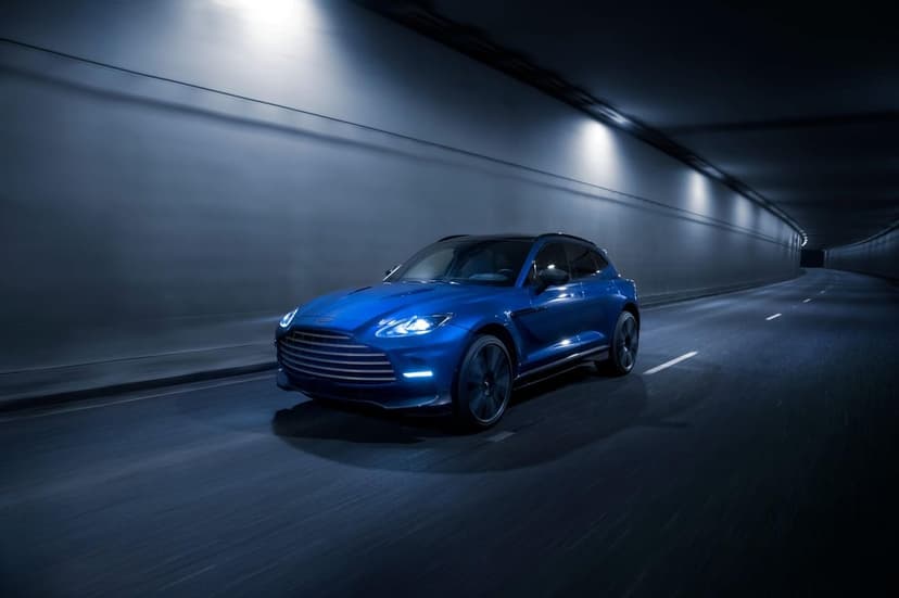 Blue Aston Martin DBX driving through a dark tunnel with glowing LED headlights and cool blue ambient lighting.