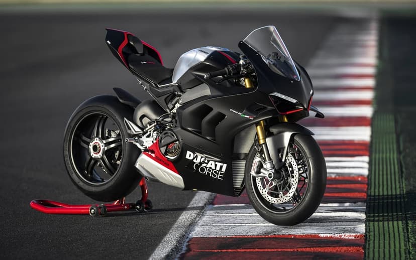 Ducati Panigale V4 SP2 sportbike in matte black and silver on a racetrack with red and white curbing.