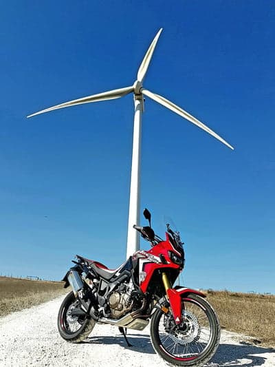 Red Motorcycle Under a Wind Turbine on a Sunny Day