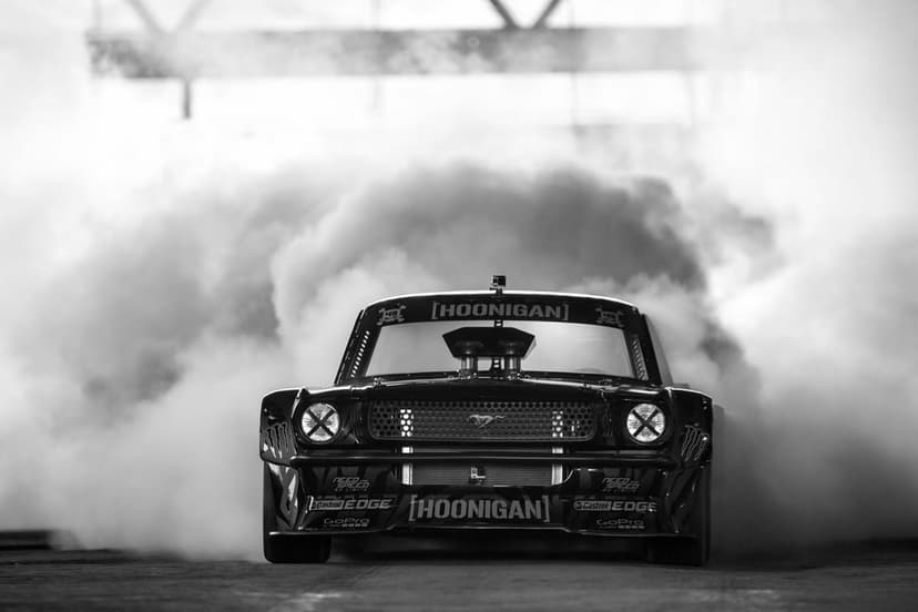 Front view of a black Mustang Hoonicorn drifting with massive clouds of white tire smoke in monochrome.