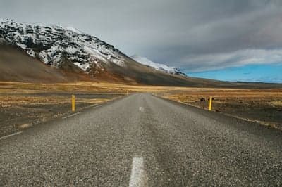 Infinite Highway Leading Toward Snow-Capped Peak Backdrop