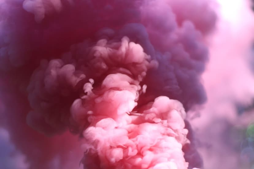 Neon pink and purple smoke clouds swirl together against a dark background with soft luminous highlights.