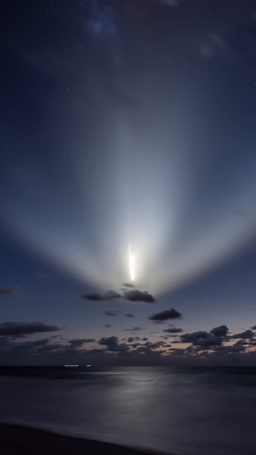 Rocket ascending through clouds at night, leaving a bright exhaust trail that reflects on the dark sea surface.