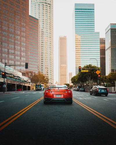 Orange Supercar Cruising Downtown Urban Mobile Wallpaper