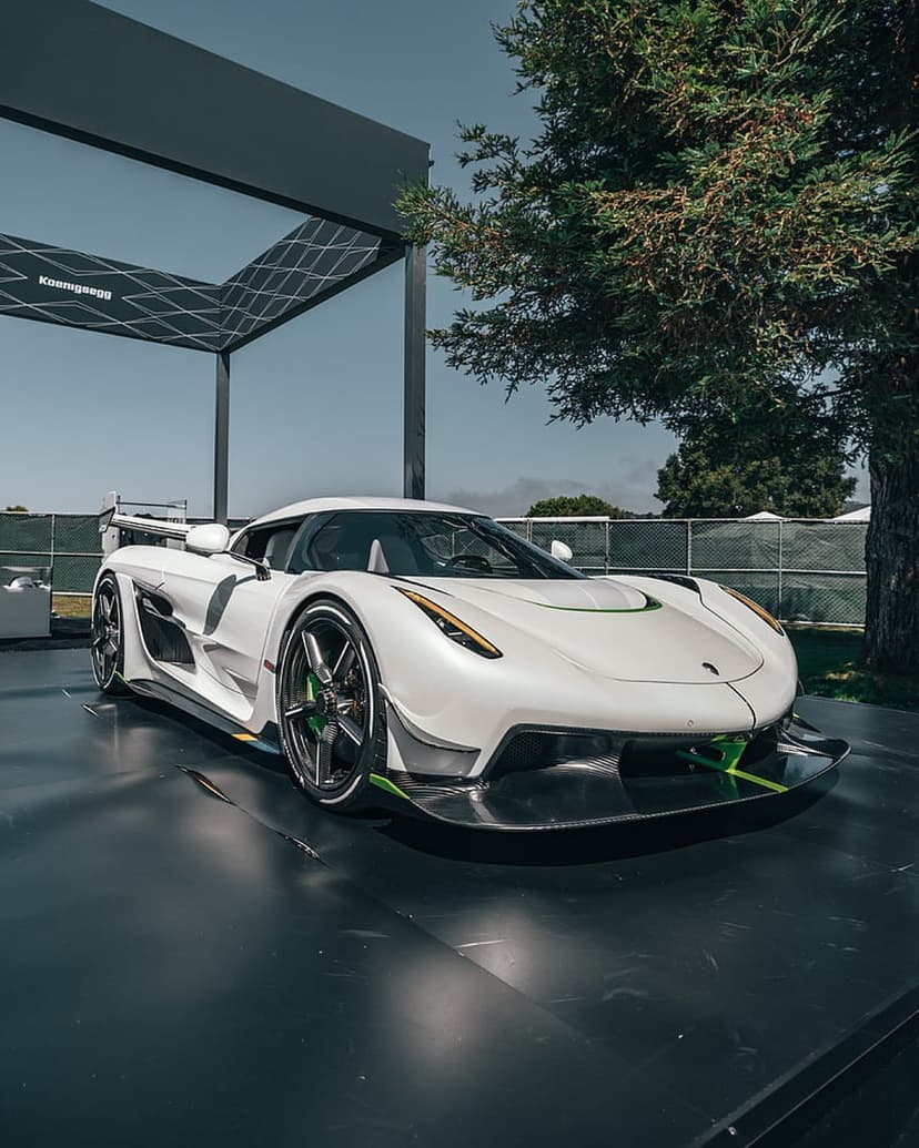 Koenigsegg Jesko Attack hypercar in white with green accents parked outdoors showing aerodynamic body details.