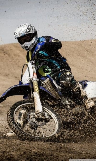 Motocross rider kicking up dirt and mud on track